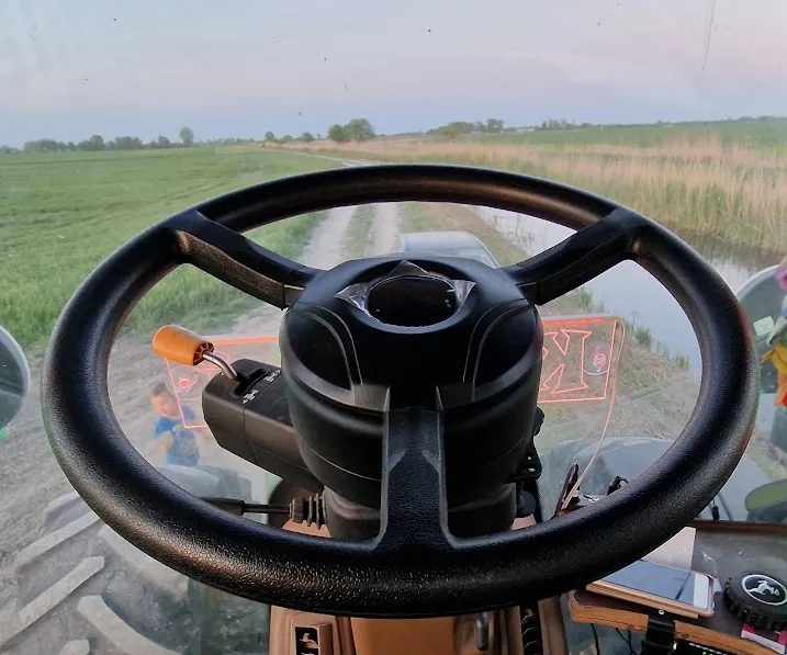 Direct drive steering motor installed in a tractor cab, view over the field