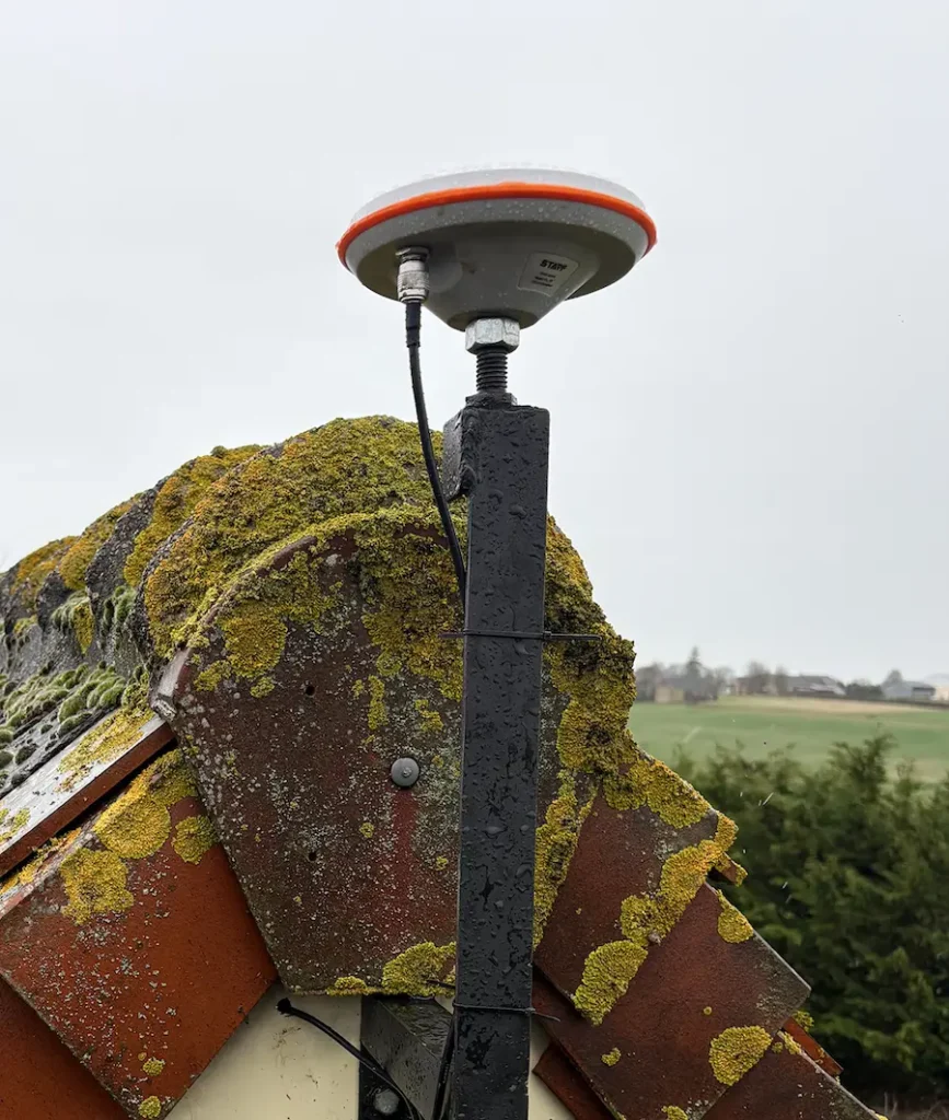 RTK GNSS base antenna mounted on a mast on a rooftop